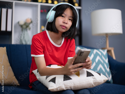 pretty girl wearing headphones using smartphone, interested child listening to favorite music, chatting in social network or playing game online.