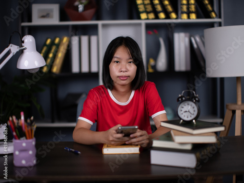 girl holding mobile phone sitting in a chair in the reading room.