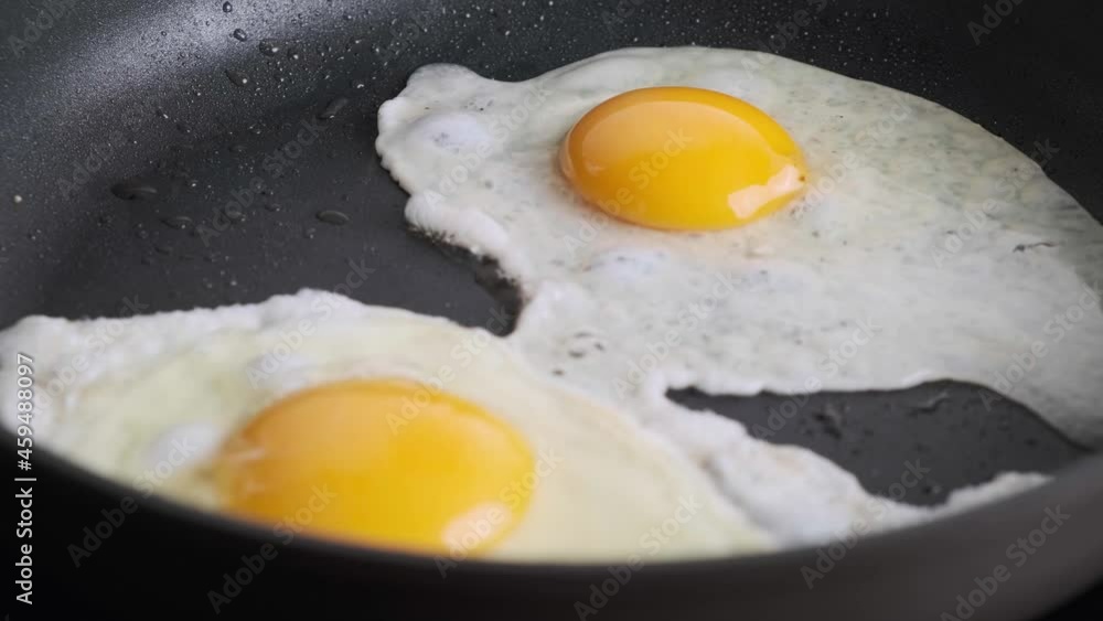 Frying eggs in black pan. Breakfast concept. Frying eggs in black pan. Breakfast concept.