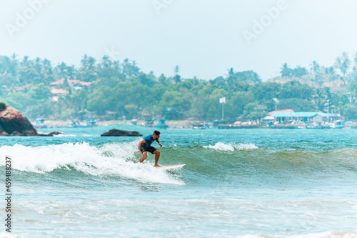 Mężczyzna surfer płynący na fali na tle błękitnego oceanu i nieba.