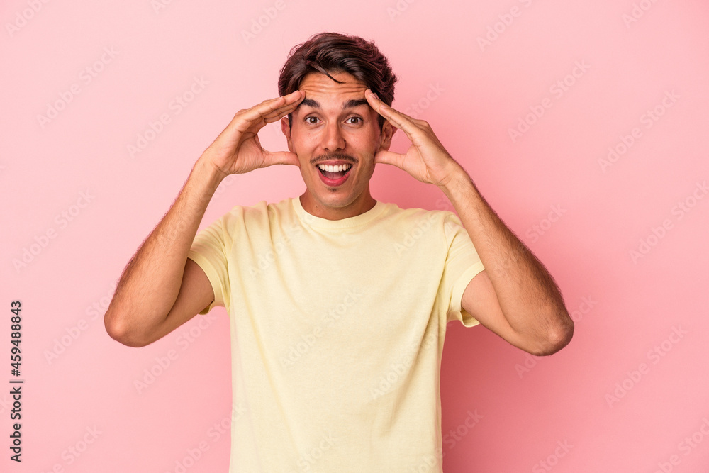 Fototapeta premium Young mixed race man isolated on white background receiving a pleasant surprise, excited and raising hands.