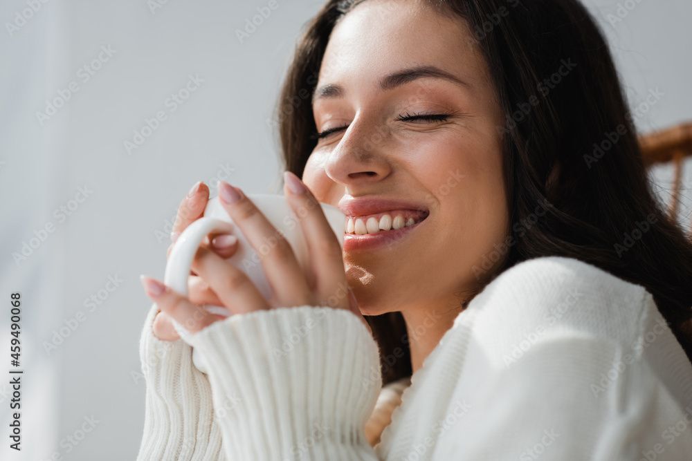 cheerful woman with closed eyes holding cup of warm tea at home cheerful woman with closed eyes holding cup of warm tea at home