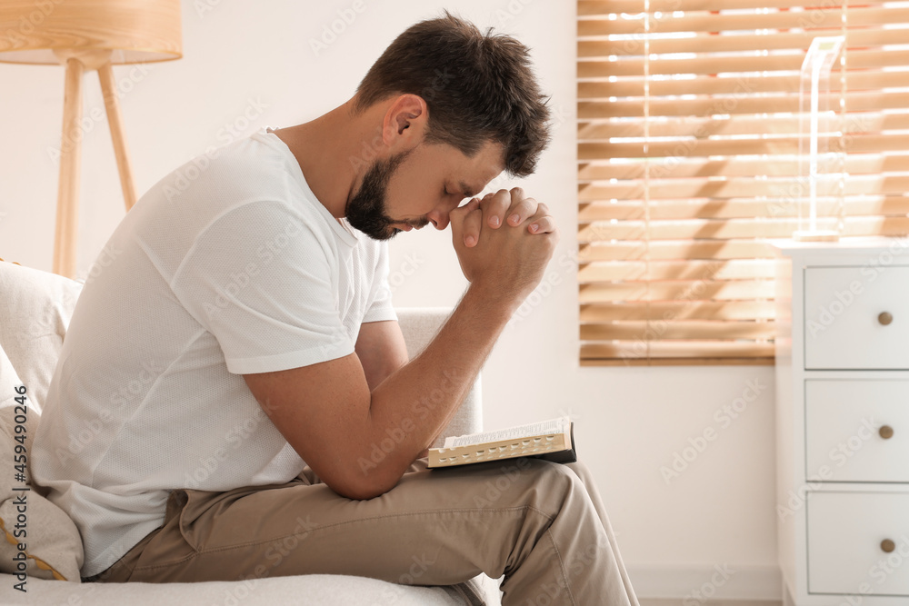 Religious man with Bible praying indoors. Space for text Religious man with Bible praying indoors. Space for text