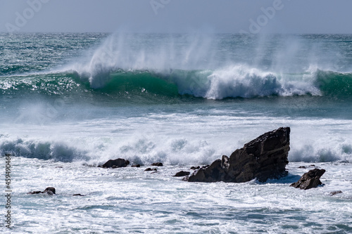 Waves and spray breaking over rocks in north Cornwall on a summer day