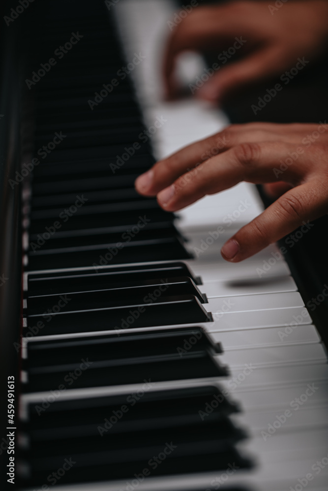 The hands of a musician playing the piano closeup in dark tones. Good for posters or media posts.