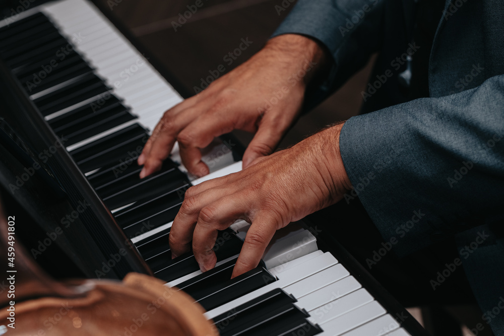 Obraz premium The hands of a musician playing the piano closeup in dark tones. Good for posters or media posts.