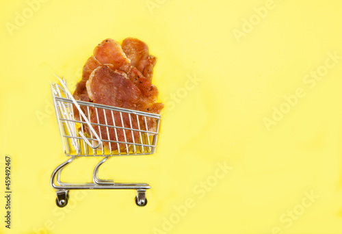 Pieces of jerky in a grocery cart on a yellow background. Copy spaes.