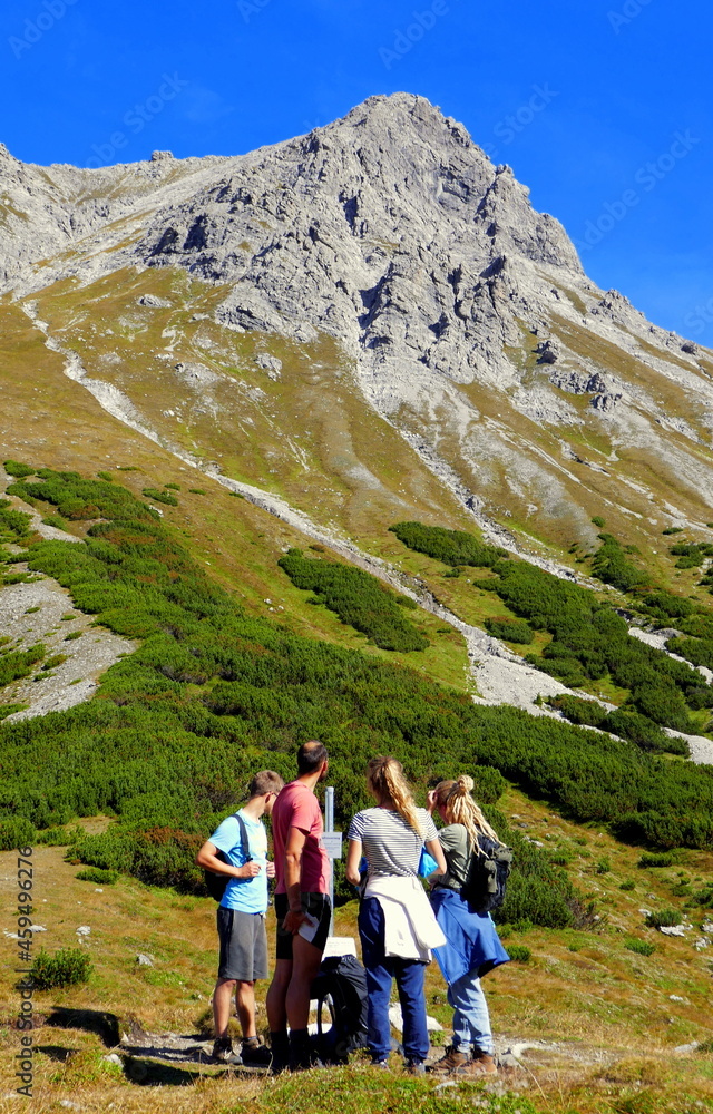 4 junge Wanderer vor dem Aufstieg zum Saulakopf im Vorarlberg mit steilem Fels und grünen Wiesen
