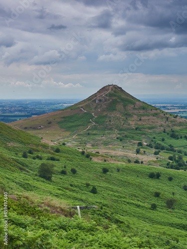 Roseberry Topping under a clouded sky, looking from the east side path, the steep, windy paths visible on its side. photo