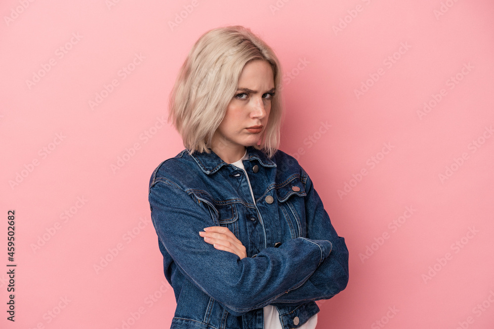 Young caucasian woman isolated on pink background frowning face in displeasure, keeps arms folded. Young caucasian woman isolated on pink background frowning face in displeasure, keeps arms folded.