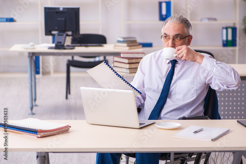 Old male employee in wheel-chair drinking coffee during break © Elnur