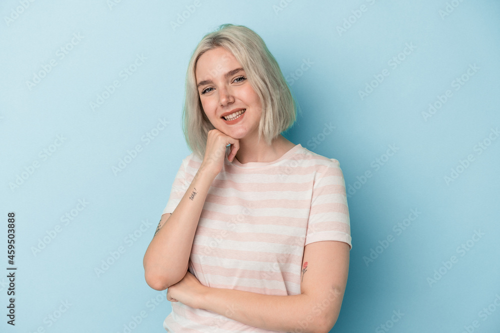 Young caucasian woman isolated on blue background smiling happy and confident, touching chin with hand. Young caucasian woman isolated on blue background smiling happy and confident, touching chin with hand.