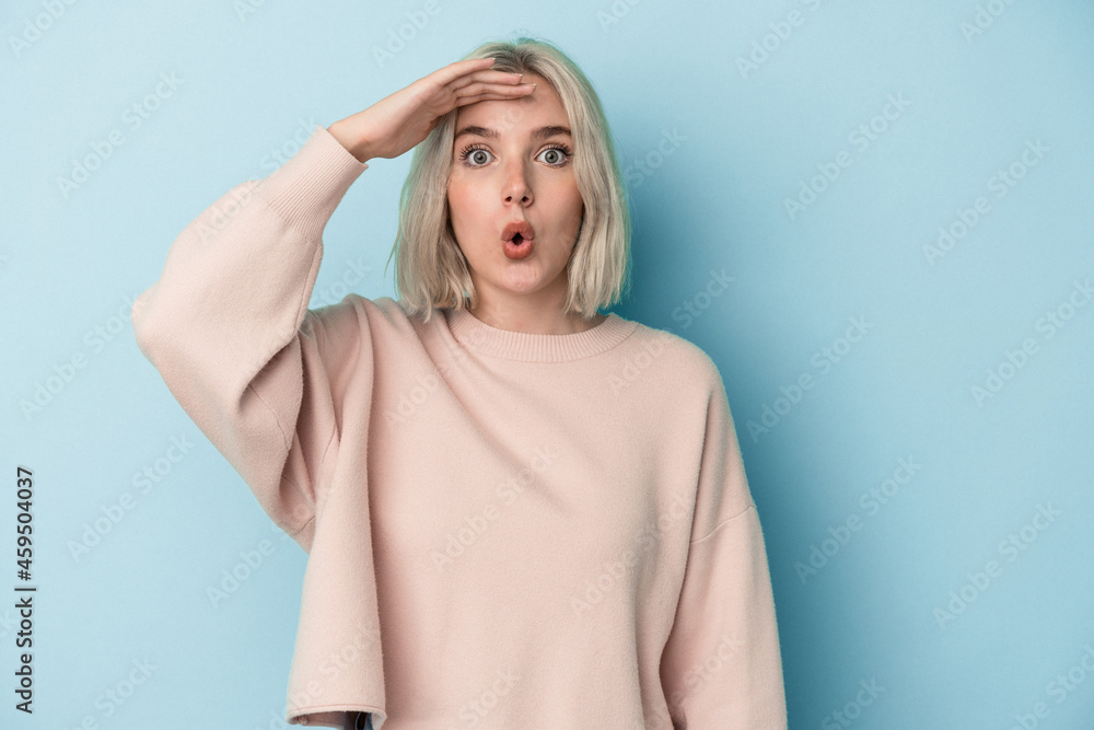 Young caucasian woman isolated on blue background looking far away keeping hand on forehead. Young caucasian woman isolated on blue background looking far away keeping hand on forehead.