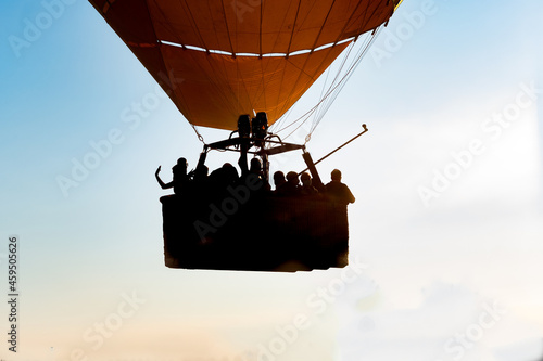 Close up of a group of people riding in a hot air balloon in the foreground and backlighting