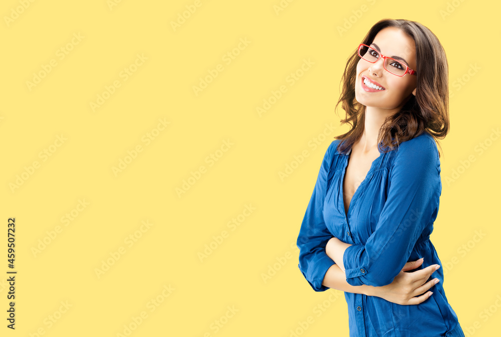Portrait of happy smiling brunette woman looking up, in red eye glasses, blue confident wear, isolated over yellow background. Studio portrait image. Copy space blank area. Portrait of happy smiling brunette woman looking up, in red eye glasses, blue confident wear, isolated over yellow background. Studio portrait image. Copy space blank area.