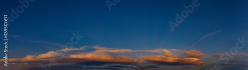 Panorama of clouds illuminated by the setting evening sun