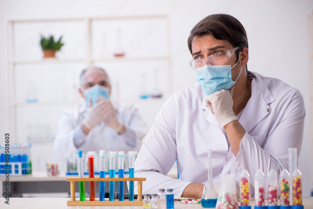 Two male chemists in drugs synthesis concept at the lab Two male chemists in drugs synthesis concept at the lab