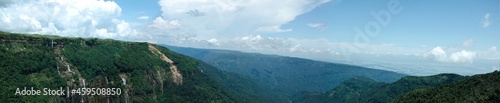 Panorama view of a landscape, mountains, low lands, waterfalls, and blue cloudy sky