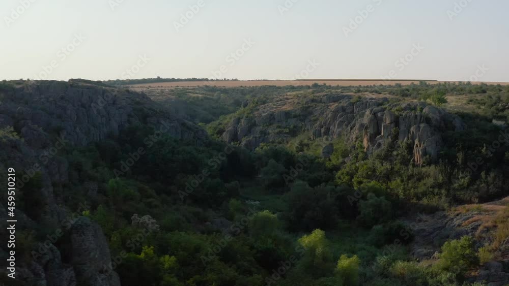 Aktovsky canyon of the Mertvovod river from a bird's eye view. Drone shooting white stone, green trees, cloudy blue sky, a shallow river flows at the bottom of the canyon. Aktovsky canyon of the Mertvovod river from a bird's eye view. Drone shooting white stone, green trees, cloudy blue sky, a shallow river flows at the bottom of the canyon.