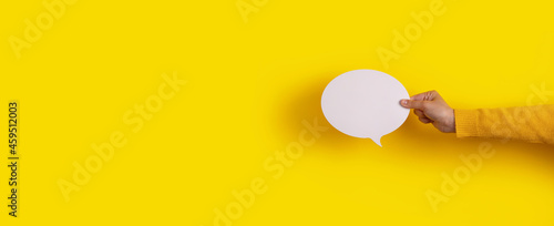 Talk bubble speech icon in hand over yellow background, panoramic layout photo