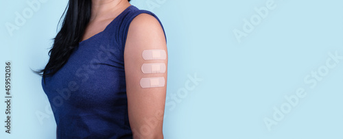 woman showing many plasters on shoulder after coronavirus vaccine, new stamps concept, mutation covid-19, panoramic layout photo