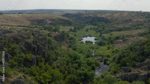 Aktovsky canyon of the Mertvovod river from a bird's eye view. Drone shooting white stone, green trees, cloudy blue sky, a shallow river flows at the bottom of the canyon. photo