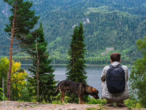 A man with a dog sitting by the lake and enjoying nature © Irina