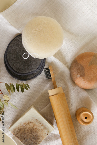 Natural eco toothbrush, soap, reusable eco bamboo make up remover pads and sponge on white towel.
