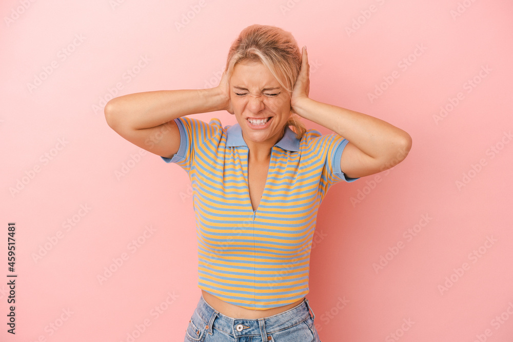 Young Russian woman isolated on pink background covering ears with hands. Young Russian woman isolated on pink background covering ears with hands.