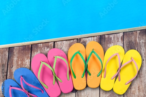 Colored flip flops sitting on the edge of a swimming pool.
