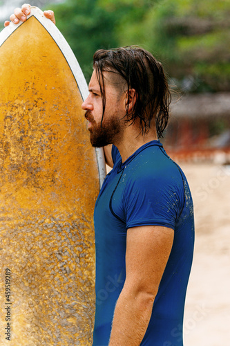 Surfer z deską na wybrzeżu przygotowujący się do pływania.