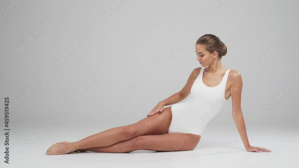 Young, beautiful, fit and natural blond woman in white swimsuit applying moisturizing cream. Massage, skin care, cellulite removal, sport and weight loss. Young, beautiful, fit and natural blond woman in white swimsuit applying moisturizing cream. Massage, skin care, cellulite removal, sport and weight loss.