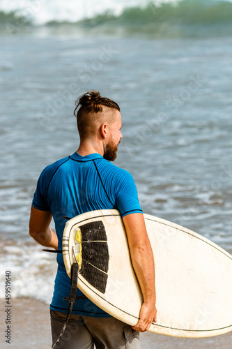 Surfer z deską na wybrzeżu przygotowujący się do pływania.