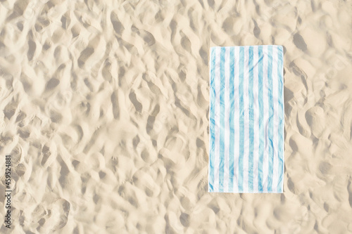 Striped beach towel on sand, aerial view. Space for text photo