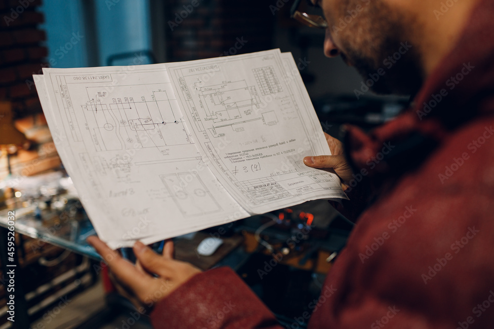 Naklejka premium Adult young engineer working on project and hold blueprint.