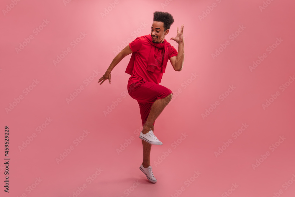Full length portrait energetic young African woman celebrating success by jumping isolated against pink background. Handsome bearded man with curly hair dressed comfortable pink clothes and sneakers. Full length portrait energetic young African woman celebrating success by jumping isolated against pink background. Handsome bearded man with curly hair dressed comfortable pink clothes and sneakers.
