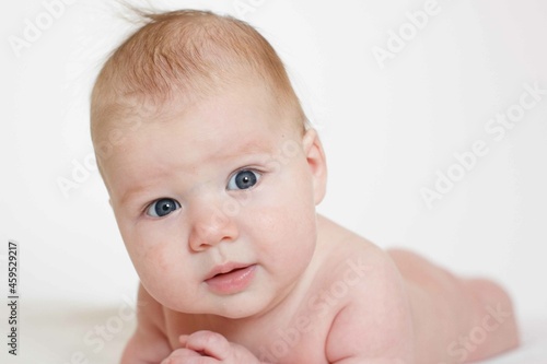 small child, baby lies on his stomach and smiles. On a white background. Newborn baby. three months old baby. A baby of European appearance. selective focus