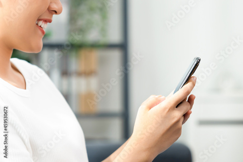 Beautiful asian woman sitting on the sofa and holding smartphone with type message on social media.