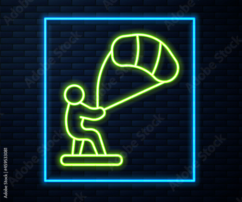 Glowing neon line Kitesurfing icon isolated on brick wall background. Vector