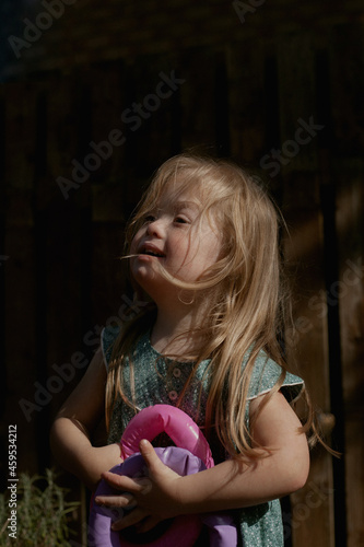 Portrait of happy little girl with Down Syndrome outdoors holding toys