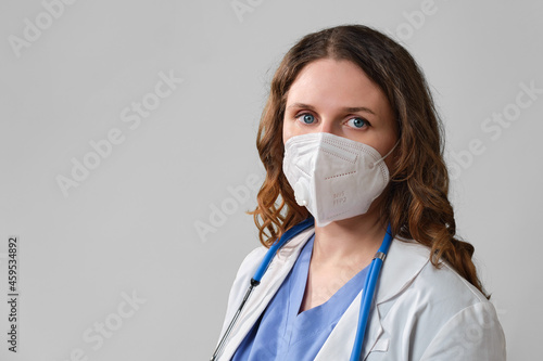 Woman doctor on a grey background. Concept of the fight against coronavirus. Face nurse in a blue uniform.