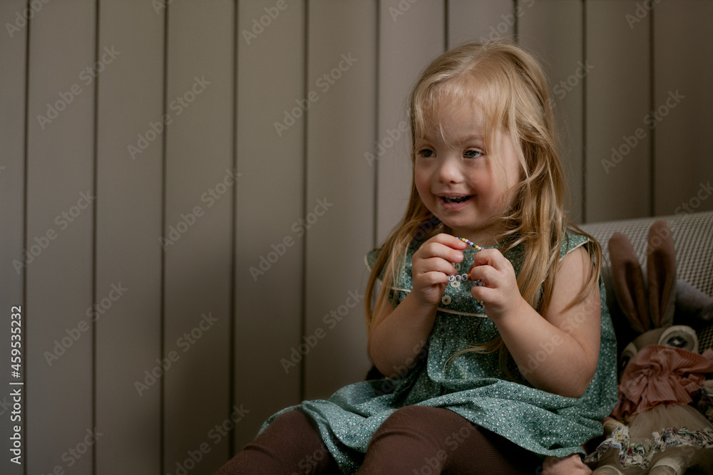 Portrait of little girl with Down Syndrome sitting on chair and