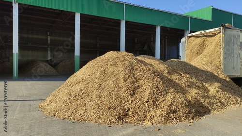 Truck unloads wood chips into a warehouse.
