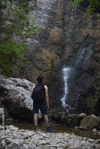 man looks at a waterfall in the valley