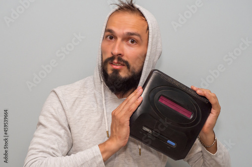 A man who grew up in the 90s is nostalgic for the times of 16-bit gameplay and holds a retro video game console in his hands