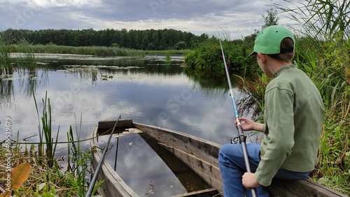 A little boy is fishing in a boat