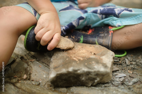 close up of child playing with rocks by hitting them against one another with dust, chips, and shards flying with shallow depth of field