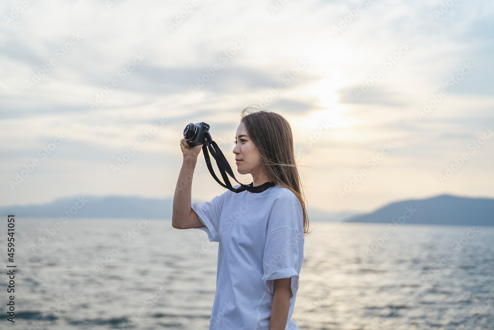 夕暮れの海で写真を撮るカメラ女子 夕暮れの海で写真を撮るカメラ女子