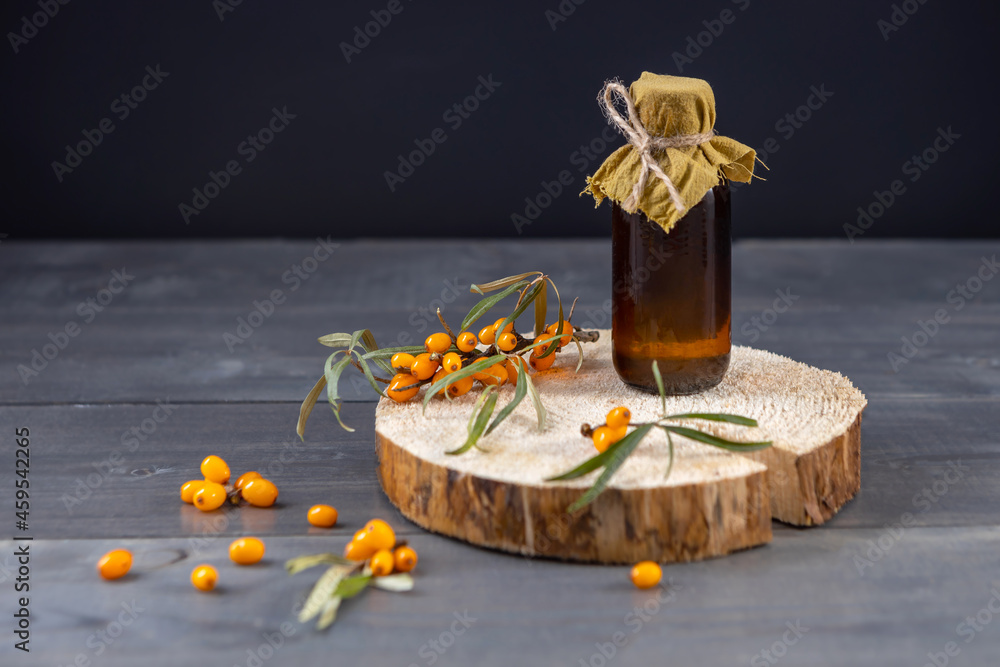 a bottle of homemade sea buckthorn oil and fresh berries on a wooden board a bottle of homemade sea buckthorn oil and fresh berries on a wooden board