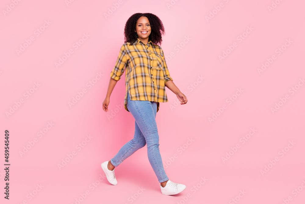 Photo of shiny charming dark skin lady wear checkered shirt walking smiling isolated pink color background Photo of shiny charming dark skin lady wear checkered shirt walking smiling isolated pink color background